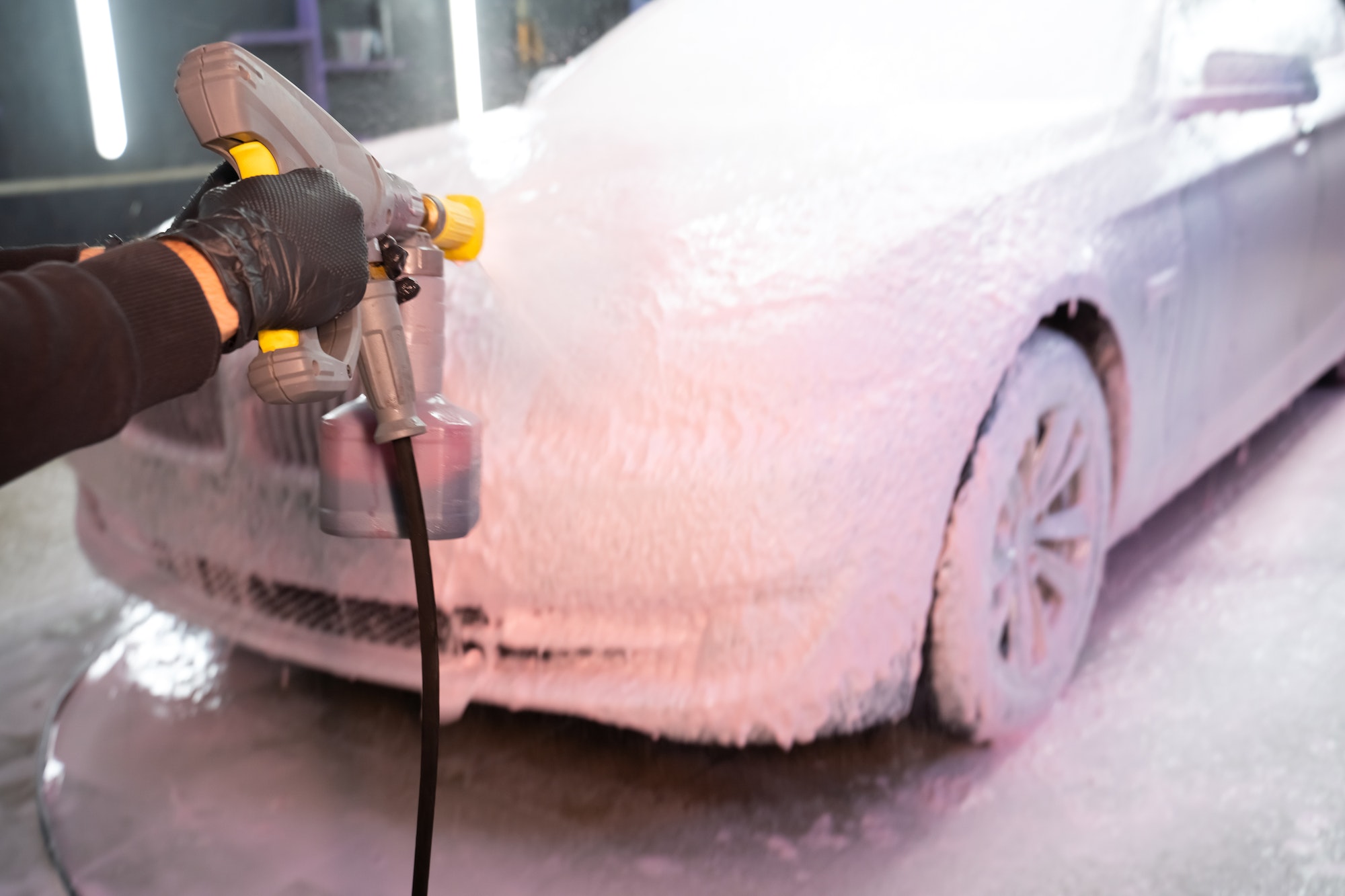Car wash employee applies foam to the car. Professional auto wash