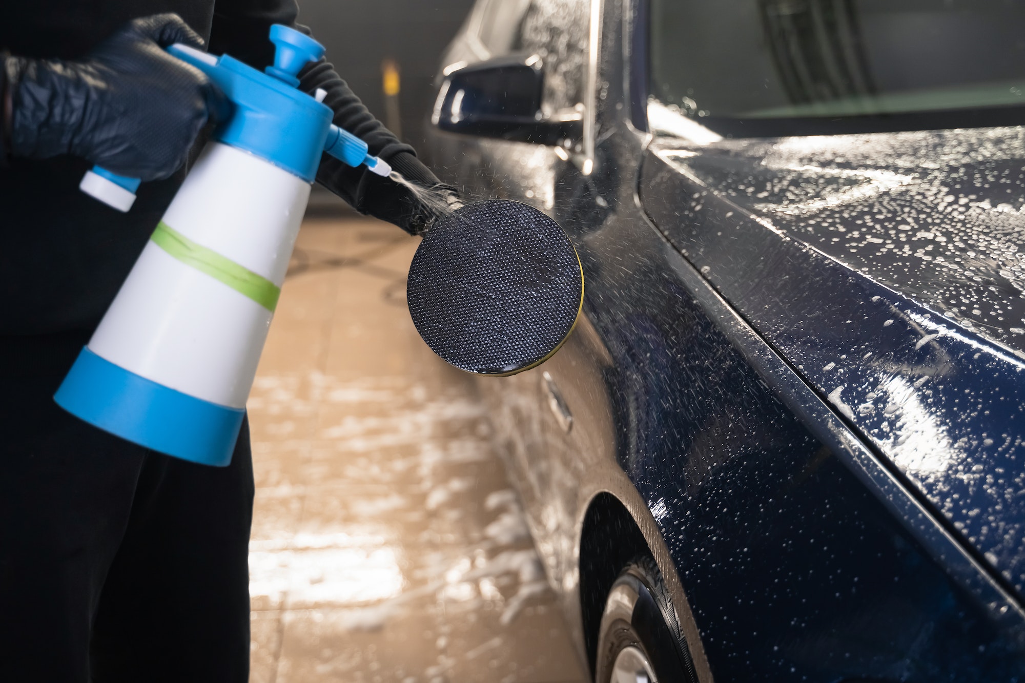 Detailing master wets car polishing sponge. Professional auto wash concept